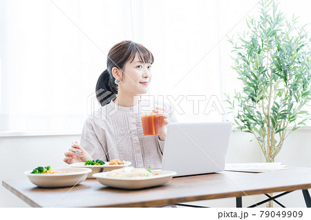 デリバリーフードを食べながらテレワークする女性 79049909