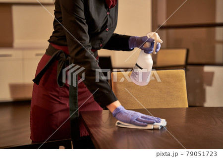 Waiter tidying a table with spray detergent Waiter tidying a table with spray detergent 79051723