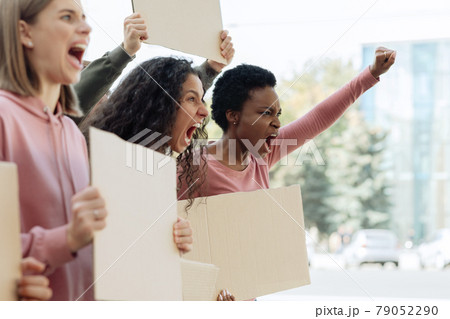 Side view of multiracial ladies with empty placards chanting slogans Side view of multiracial ladies with empty placards chanting slogans 79052290