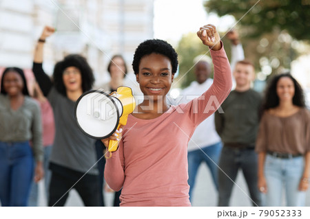 Positive black lady activist with megaphone on the street Positive black lady activist with megaphone on the street 79052333