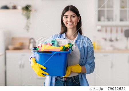 Young housewife holding bucket with cleaning supplies tools Young housewife holding bucket with cleaning supplies tools 79052622