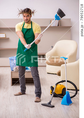 Young male contractor wearing prickly wreath on head cleaning th 79052718