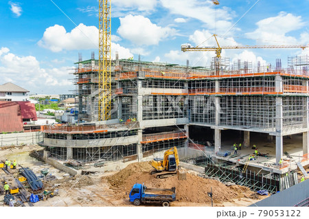 Construction site. Construction cranes and high-rise building under construction against blue sky. 79053122