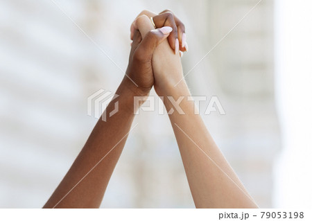 Unrecognizable african american and caucasian ladies holding hands Unrecognizable african american and caucasian ladies holding hands 79053198