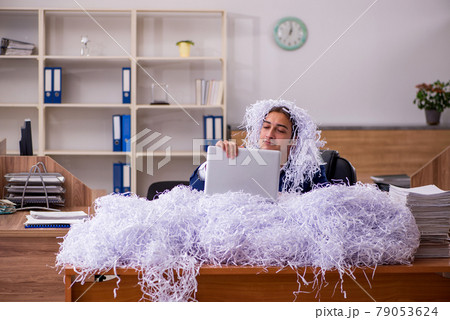 Young male employee and a lot of cut papers in the office 79053624
