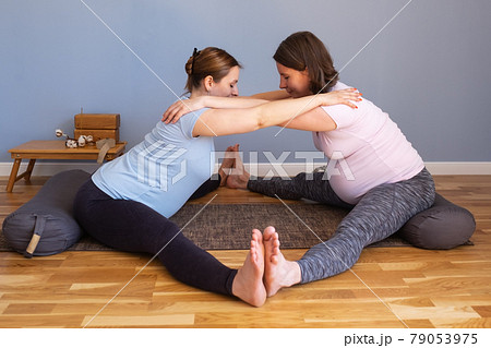 Pregnant women working out idoing Seated straddle posture, Upavishtha Konasana 79053975