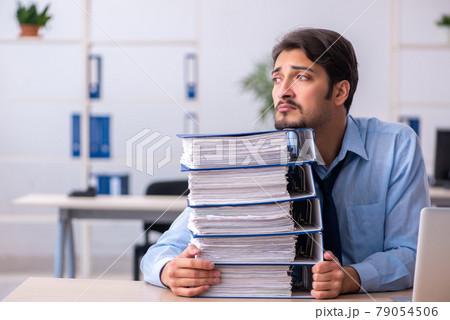 Young male employee and too much work in the office 79054506