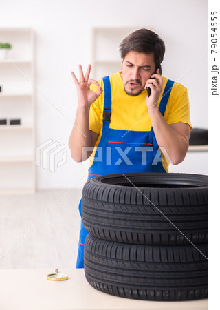 Young male garage worker with tyre at workshop Young male garage worker with tyre at workshop 79054555