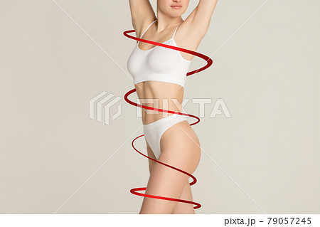 Beautiful slim tanned wonan in white underwear isolated on gray background. Grace, medicine and beauty concept. Beautiful slim tanned wonan in white underwear isolated on gray background. Grace, medicine and beauty concept. 79057245