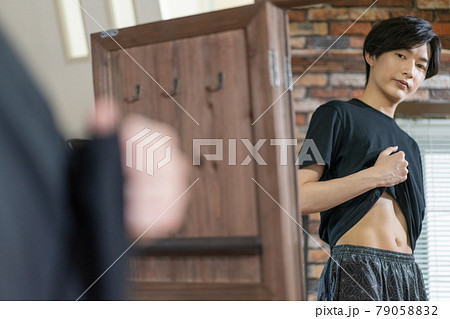 鏡でお腹の贅肉をチェックする若い男性 79058832