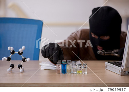 Young man in balaclava stealing vaccine from the lab Young man in balaclava stealing vaccine from the lab 79059957