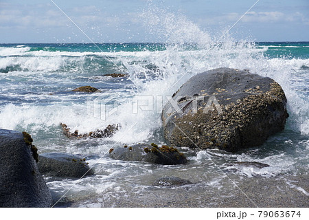 岩にぶつかって起こる波しぶきの写真素材