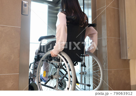 Disabled woman in wheelchair entering elevator back view Disabled woman in wheelchair entering elevator back view 79063912