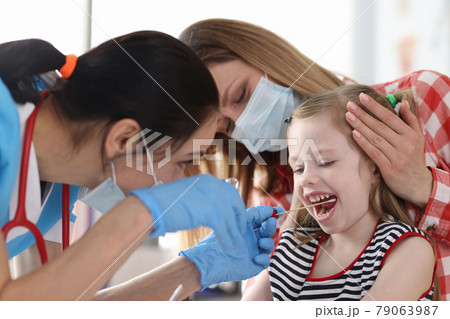 Doctor in protective medical mask taking buccal swab from little girl with cotton swab Doctor in protective medical mask taking buccal swab from little girl with cotton swab 79063987