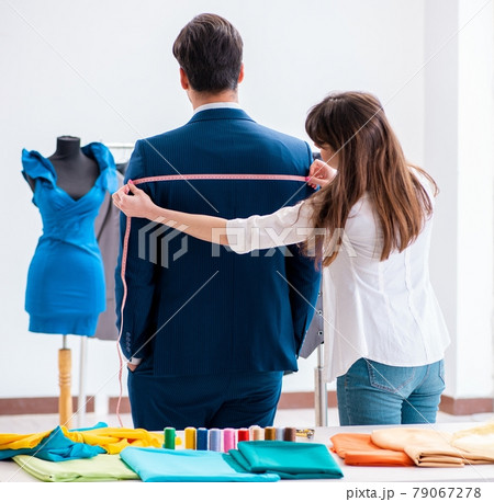 Professional tailor taking measurements for formal suit 79067278