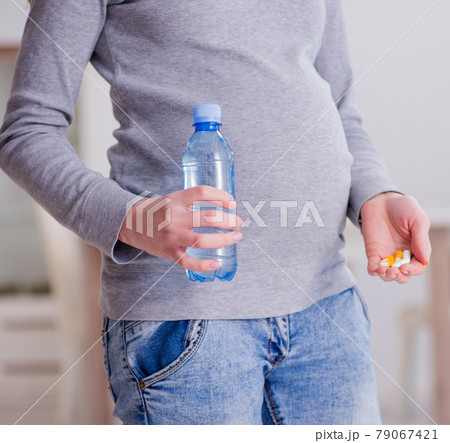 Pregnant woman taking pills during pregnancy Pregnant woman taking pills during pregnancy 79067421