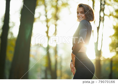 Pretty woman in sport outfit posing on camera at park 79070166