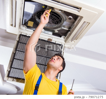 Repairman repairing ceiling air conditioning unit Repairman repairing ceiling air conditioning unit 79071275