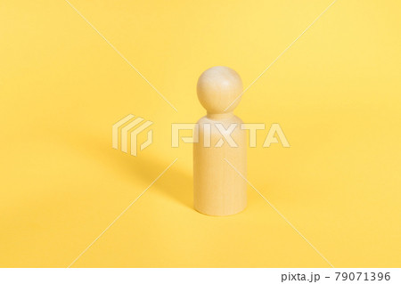 One wooden figure stands alone on yellow backdrop isolated. Confident person, mentor, coach, leader concept One wooden figure stands alone on yellow backdrop isolated. Confident person, mentor, coach, leader concept 79071396