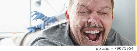 Man lying on couch with his mouth open. Nurse giving injection in buttock Man lying on couch with his mouth open. Nurse giving injection in buttock 79071954