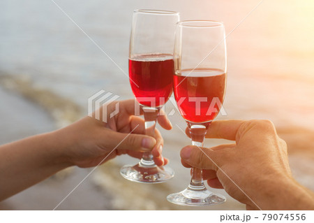 Two red wine glasses in couple hands silhouettes against sea sunset. Two red wine glasses in couple hands silhouettes against sea sunset. 79074556