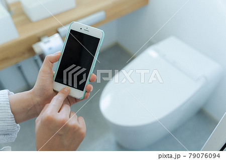 トイレとスマホを持つ手元 79076094