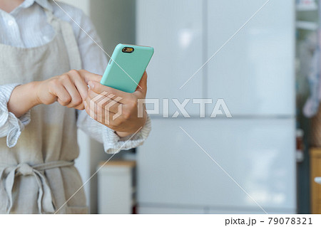スマホを持つ主婦の手元 79078321