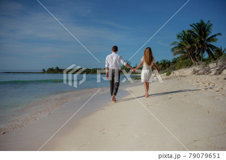 A man and a woman walk on the seashore and look at the horizon. 79079651