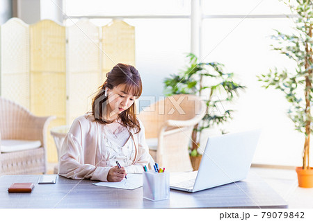 自宅のリビングルームでリモートワークをしている女性 自宅のリビングルームでリモートワークをしている女性 79079842