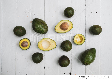 Whole and halved avocado on wooden table  79080384
