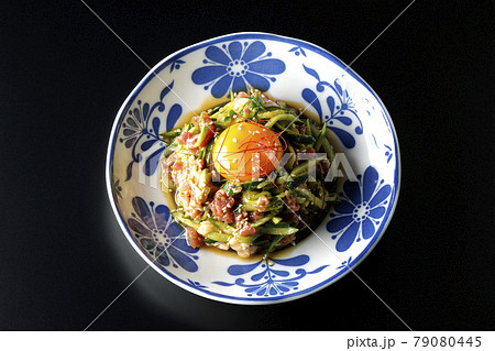 卵黄や糸唐辛子やいり胡麻が乗っている胡瓜と生ハムのユッケを黒背景で俯瞰撮影 卵黄や糸唐辛子やいり胡麻が乗っている胡瓜と生ハムのユッケを黒背景で俯瞰撮影 79080445