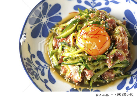 卵黄や糸唐辛子やいり胡麻が乗っている胡瓜と生ハムのユッケを白背景で俯瞰撮影 79080640