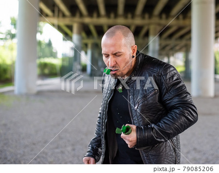 Bald Caucasian man eating broken glass. The bandit is eating a bottle of sugar. Joke or magic 79085206