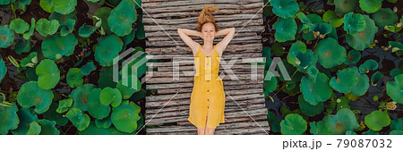BANNER, LONG FORMAT Young woman in a yellow dress on the path among the lotus lake. Mua Cave, Ninh Binh, Vietnam. Vietnam reopens after quarantine Coronovirus COVID 19 concept 79087032