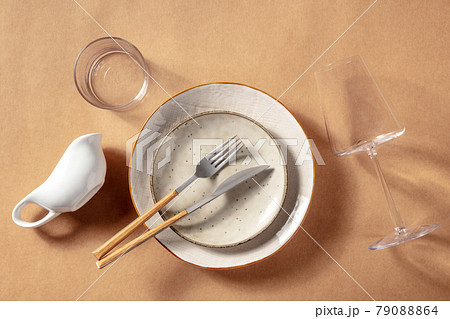 Modern tableware set. Ceramic plates, a wine glass, and cutlery Modern tableware set. Ceramic plates, a wine glass, and cutlery 79088864