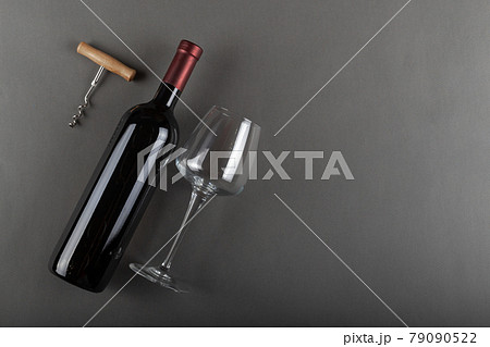 Corked red wine bottle, corkscrew and empty wine glass on gray background. Corked red wine bottle, corkscrew and empty wine glass on gray background. 79090522