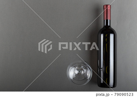 Corked bottle of red wine and empty wine glass on gray background. 79090523