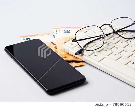 Euro money banknotes, keyboard, smartphone and glasses, online banking, business, student loan concept Euro money banknotes, keyboard, smartphone and glasses, online banking, business, student loan concept 79090615