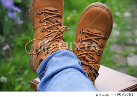 Brown boots and jeans on the legs. Legs are crossed on the stool. 79091061
