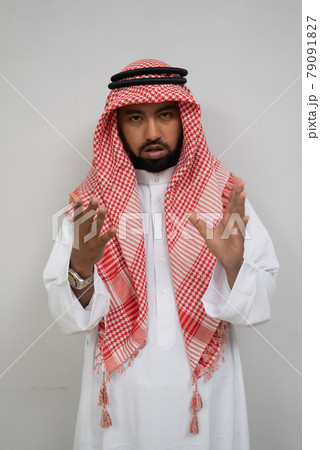an arabian young man standing looking at the camera with hand gestures while talking 79091827