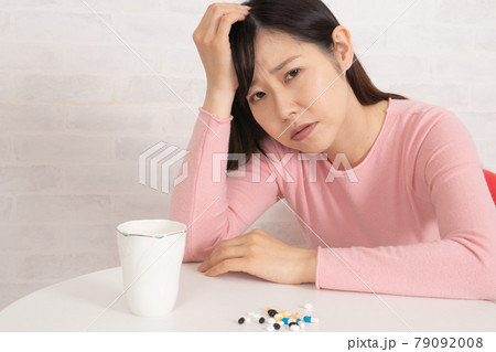 大量の薬と ふさぎこむ鬱状態な女性 鬱病イメージ の写真素材