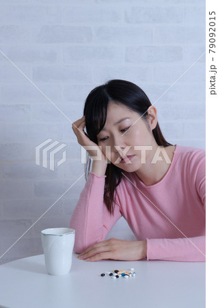 大量の薬と、ふさぎこむ鬱状態な女性(鬱病イメージ) 大量の薬と、ふさぎこむ鬱状態な女性(鬱病イメージ) 79092015