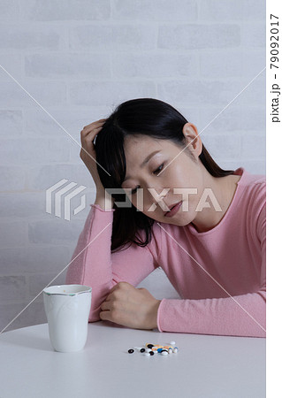 大量の薬と ふさぎこむ鬱状態な女性 鬱病イメージ の写真素材