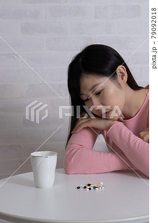 大量の薬と、ふさぎこむ鬱状態な女性(鬱病イメージ) 大量の薬と、ふさぎこむ鬱状態な女性(鬱病イメージ) 79092018