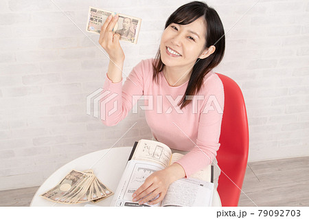 株やFX投資の勉強をして、ぼろ儲けして札束を握る女性 79092703