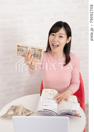 株やFX投資の勉強をして、ぼろ儲けして札束を握る女性 79092708