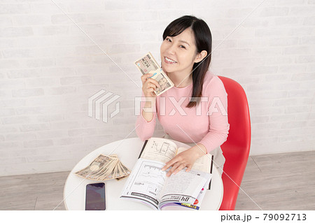 株やFX投資の勉強をして、ぼろ儲けして札束を握る女性 79092713