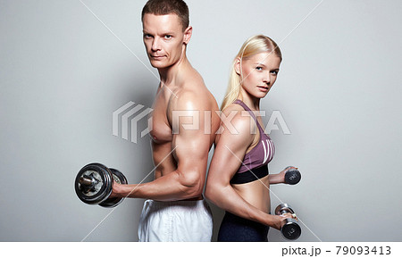 muscular Man and beautiful blond girl with dumbbells. Gym. Sport couple muscular Man and beautiful blond girl with dumbbells. Gym. Sport couple 79093413