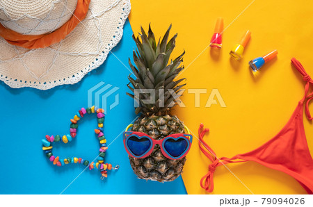 Summer composition. Pineapple in sunglasses, hat, beads and nail polishes on a yellow background with copy space. Vacation concept. Flat lay. 79094026