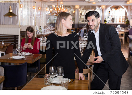 Gentleman helping woman with her chair in restaurant 79094543